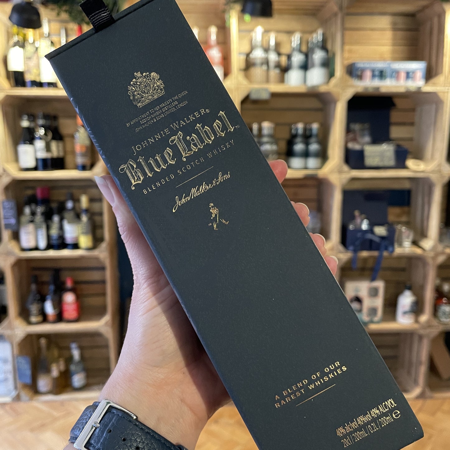 The front of a box of Johnnie Walker Blue Label Whisky 20cl Bottle on a table with shop shelves in the background in Barry Island Spirits Co shop on High Street in Barry