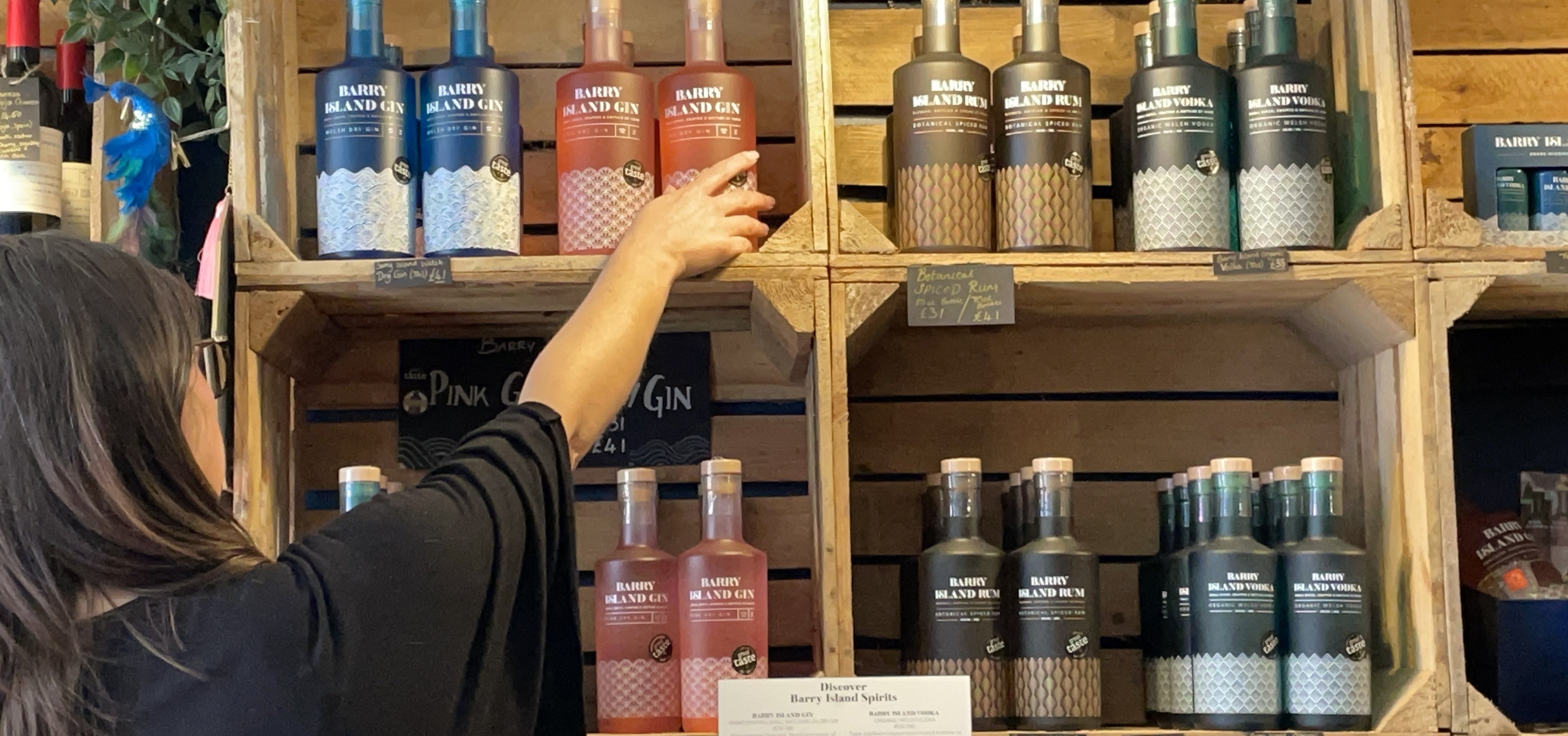 A woman reaching for a bottle of Barry Island Gin in a shop