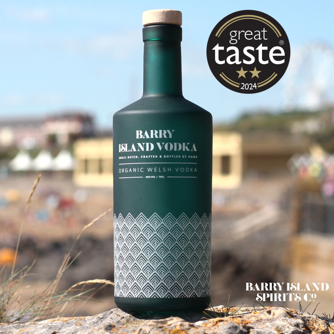 A bottle of Barry Island Vodka on Barry Island Beach with a 2-star Great Taste Award logo