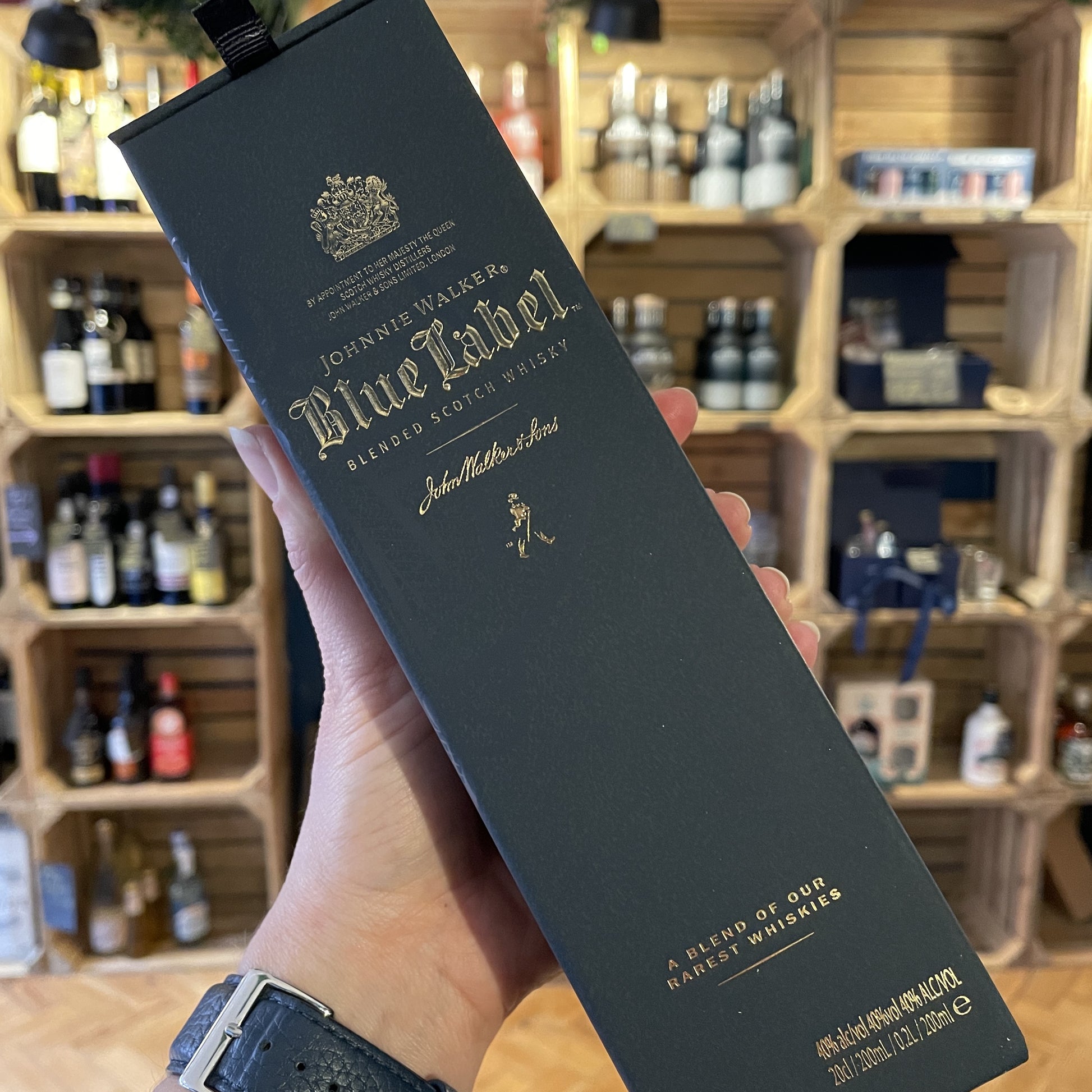 The front of a box of Johnnie Walker Blue Label Whisky 20cl Bottle on a table with shop shelves in the background in Barry Island Spirits Co shop on High Street in Barry