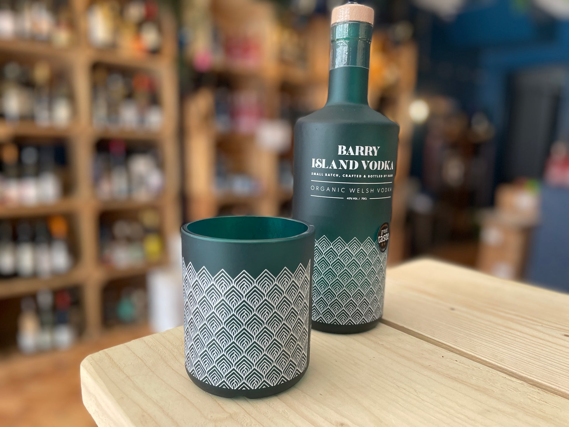 An upcycled Barry Island Vodka Glass and a bottle of Barry Island Vodka on a table in a shop