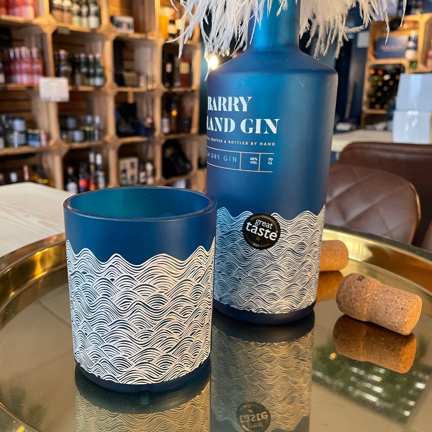 An upcycled Barry Island Gin Glass and a bottle of Barry Island Welsh Dry Gin on a table in a shop
